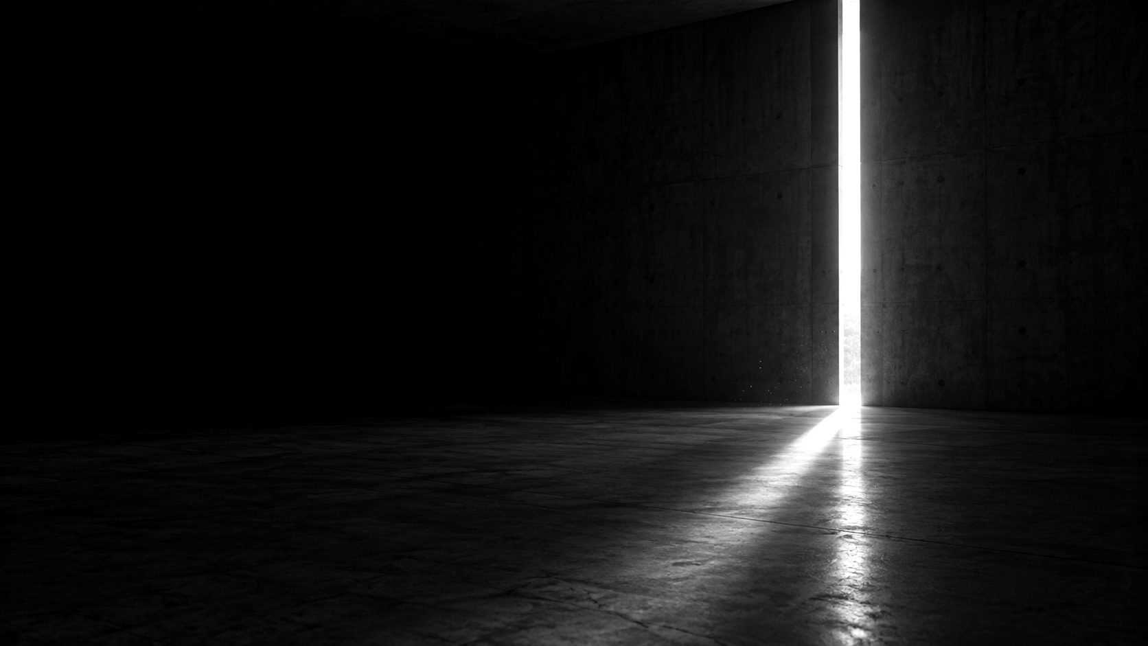 A thin slit of light entering a dark concrete room